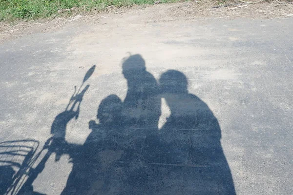 shadow of 3 people on asphalt riding electric bicycle