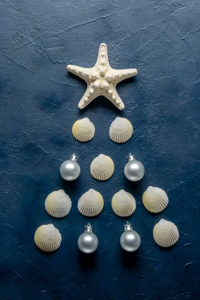 Árbol de Navidad de conchas de mar y estrellas de mar sobre fondo azul, vista superior — Foto de Stock