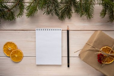Dilek ya da alışveriş listesi konsepti. Tahta zemin üzerine beyaz kağıt not defteri hediye ve köknar ağacı