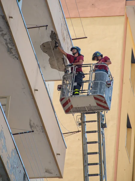 Bomberos trabajando para poner la incertidumbre de una cornisa — Foto de Stock