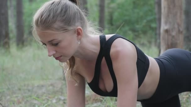 Гибкая тонкая женщина практикует йогу, выполняет раджакапотасану в сосновом лесу — стоковое видео