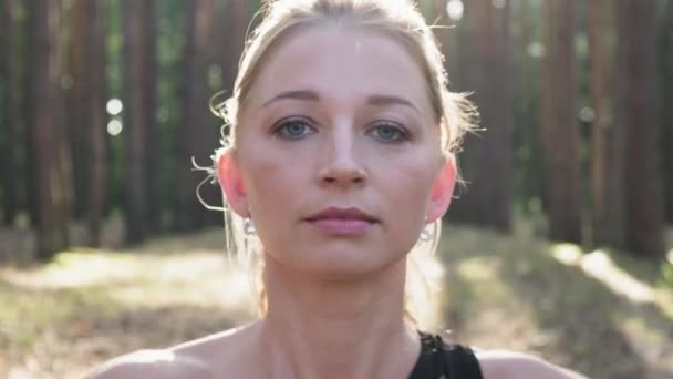 Young fit woman making namaste gesture in lotus pose, closing eyes at forest — Stock Video