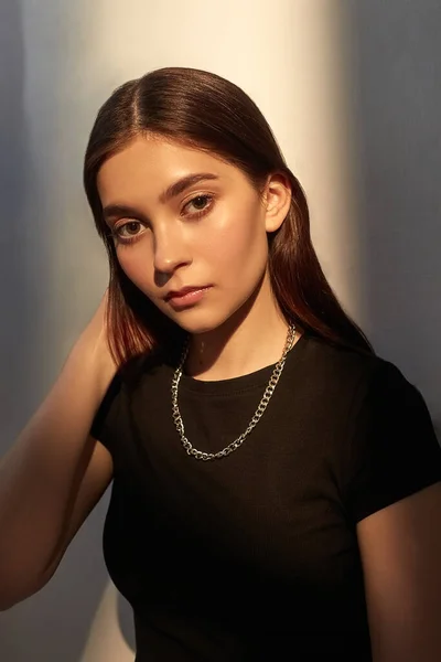 Porträtt av ung kaukasisk dam med långt hår, metall glänsande kedja i svart topp — Stockfoto