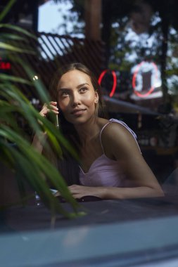 Güzel bayan telefonla arıyor. Kafenin dışındaki cam kırıklarından vurulmuş.