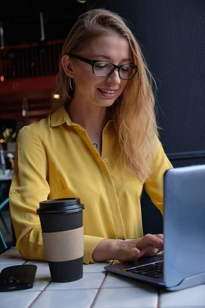 Νεαρή καυασιάτισσα όμορφη γυναίκα κάθεται σε καφετέρια, πληκτρολογώντας σε πληκτρολόγιο laptop — Φωτογραφία Αρχείου