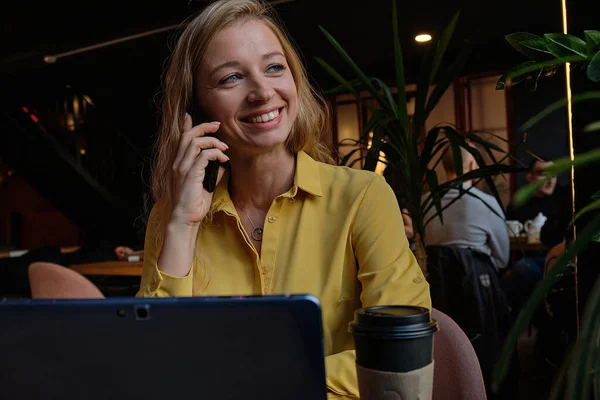 Νεαρή καυασιάτισσα όμορφη γυναίκα σε καφετέρια με φορητό υπολογιστή, καλώντας από το smartphone — Φωτογραφία Αρχείου
