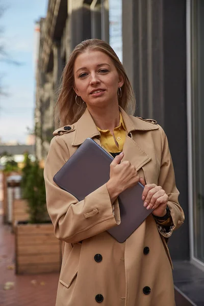 Νεαρή καυκάσια γυναίκα σε παλτό κρατώντας δισκίο, φορητό υπολογιστή ή ebook σε εξωτερικούς χώρους χέρια — Φωτογραφία Αρχείου