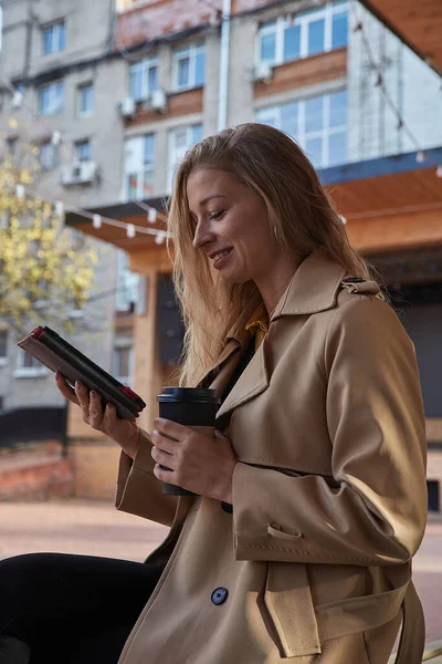 Kaukasiska ung kvinna i päls med hjälp av tablett utomhus på solig dag, läsa e-bok — Stockfoto