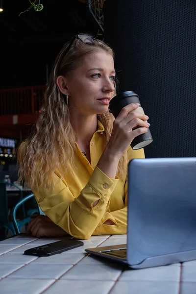 Νεαρή καυασιάτισσα όμορφη γυναίκα κάθεται στο καφέ με φορητό υπολογιστή και φλιτζάνι καφέ — Φωτογραφία Αρχείου