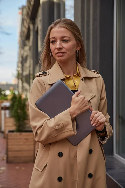 Νεαρή καυκάσια γυναίκα σε παλτό κρατώντας δισκίο, φορητό υπολογιστή ή ebook σε εξωτερικούς χώρους χέρια — Φωτογραφία Αρχείου