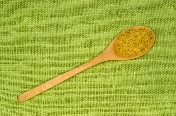 Fenugreek seeds in a spoon on green leaf — Stock Photo, Image