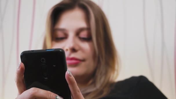 Fiatal gyönyörű lány sms-ezik a telefonon — Stock videók