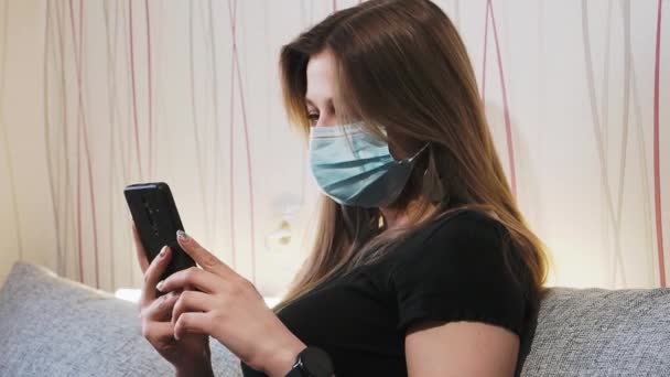 Jovem bela mulher vídeo chamando vestindo máscara facial médica — Vídeo de Stock