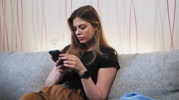 Fiatal gyönyörű lány sms-ezik a telefonon — Stock videók
