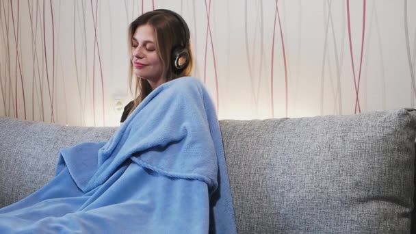 Κορίτσι που ακούει μουσική με ακουστικά στο σπίτι στον καναπέ Βίντεο Κλιπ