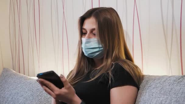 Une femme masquée nettoie le téléphone à la maison Séquence Vidéo Libre De Droits
