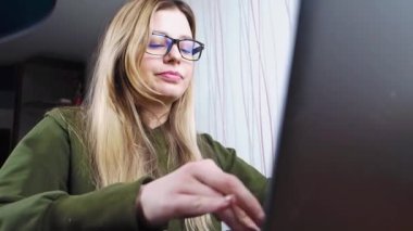 Gözlüklü genç kız dizüstü bilgisayarda çalışıyor.