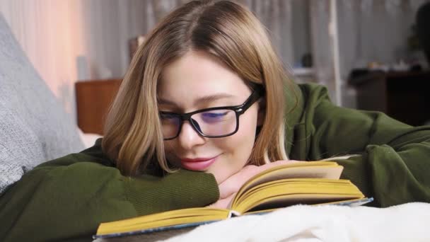 Молода красива жінка в окулярах читає книгу — стокове відео