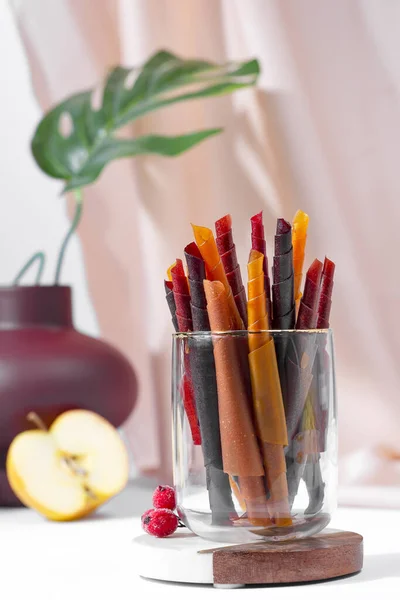 Rolos de couro de frutas coloridas em uma placa no fundo claro — Fotografia de Stock