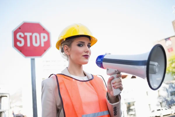 Serious businesswoman wearing builders clothes holding megaphone — Stock Photo, Image