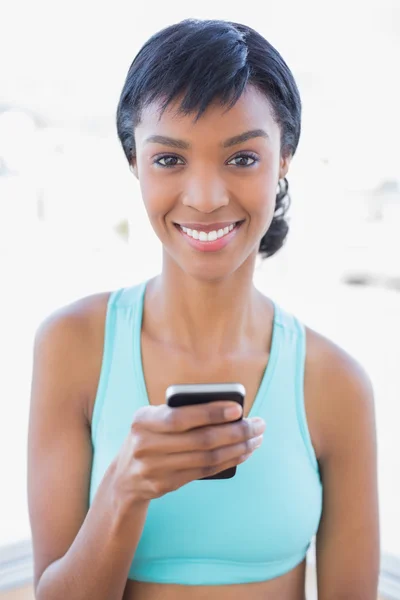 Encantada mujer en forma mensajes de texto con su teléfono móvil —  Fotos de Stock