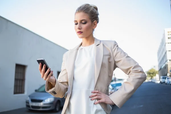 Ernsthafte elegante Geschäftsfrau schaut auf ihr Smartphone — Stockfoto