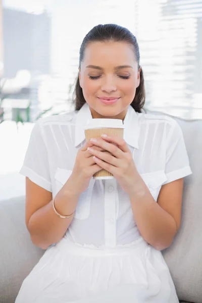 Ontspannen mooie vrouw met koffie zittend op gezellige Bank — Stockfoto