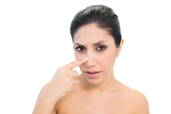 Worried brunette pointing to nose and looking at camera — Stock Photo, Image