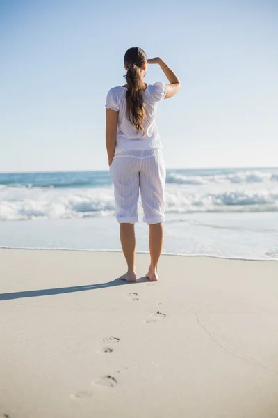 Bakifrån av vackra brunett på stranden tittar bort — Stockfoto