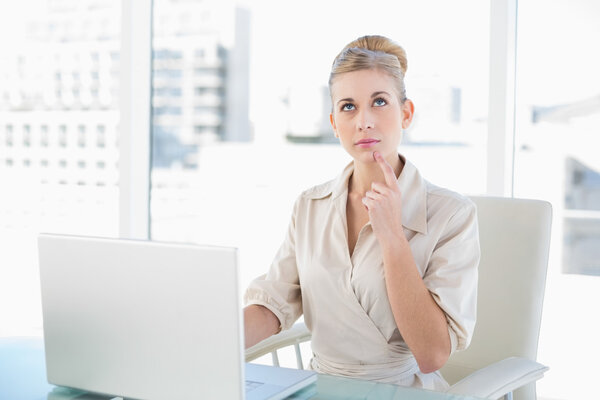 Wondering young blonde businesswoman using a laptop