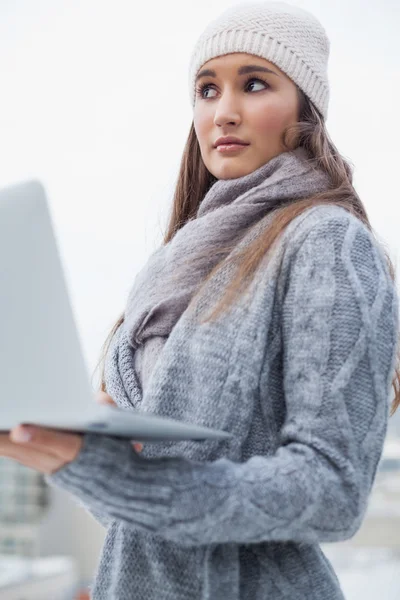 Femme réfléchie avec des vêtements d'hiver sur l'utilisation de son ordinateur portable — Photo