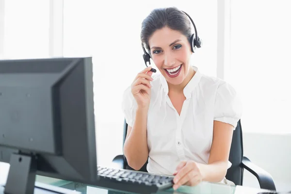 Glad call centre agent sitter vid hennes skrivbord på ett samtal — Stockfoto