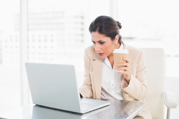 在笔记本电脑上工作时集中的女商人喝咖啡 — 图库照片
