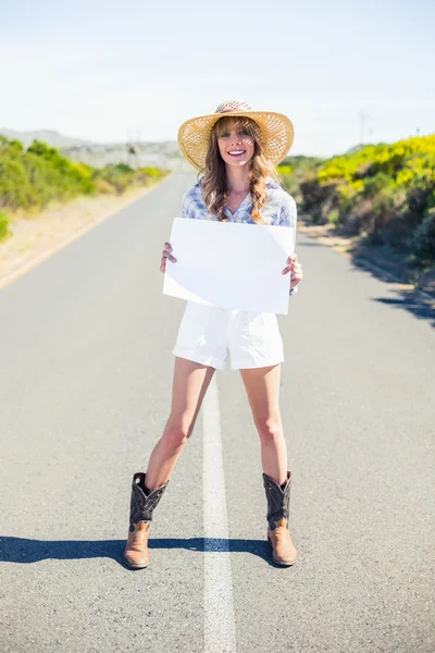 Cheerful blonde holding sign while hitchhiking on the road — Stock Photo, Image