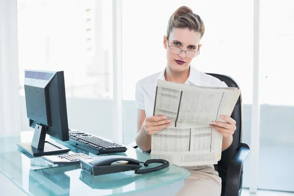 Serious businesswoman wearing glasses holding a newspaper — Stock Photo, Image