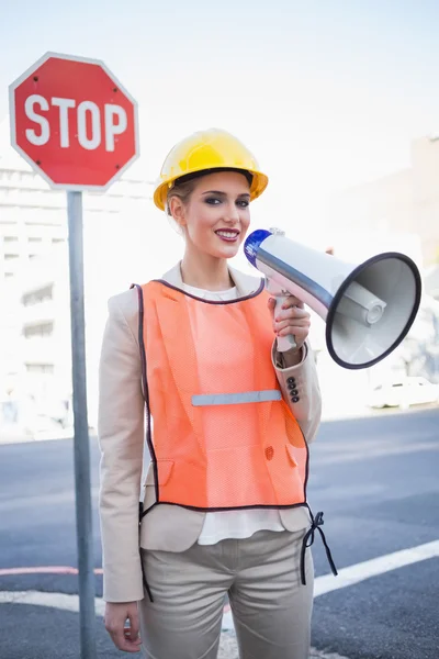 Empresária sorridente vestindo roupas de construtores gritando em megap — Fotografia de Stock