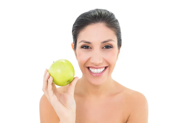 Happy brunette holding a green apple and looking at camera — Stock Photo, Image