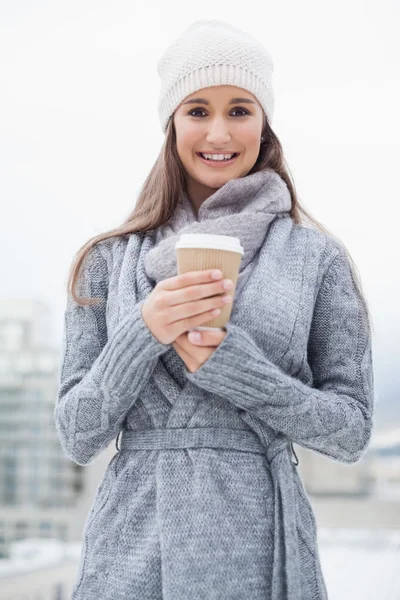 Smiling pretty brunette with winter clothes on holding coffee — Stock Photo, Image