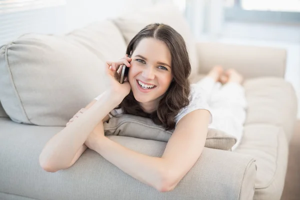 Lachende leuke vrouw liggend op een gezellige Bank hebben een telefoongesprek — Stockfoto