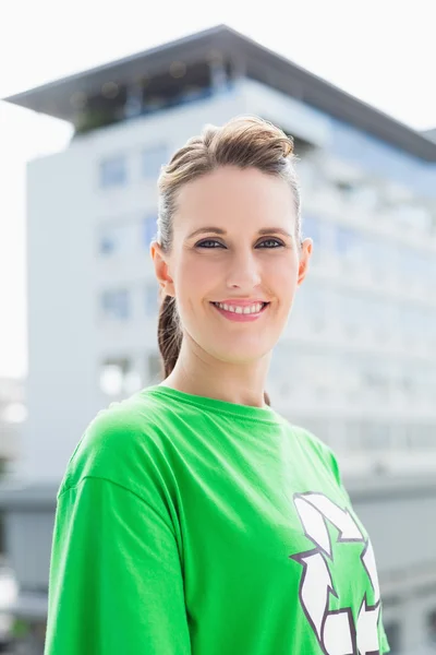 Femme souriante portant une chemise verte avec un symbole de recyclage dessus — Photo