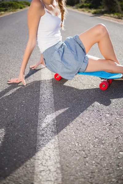 Body of young woman sitting on her skateboard — Stock Photo, Image