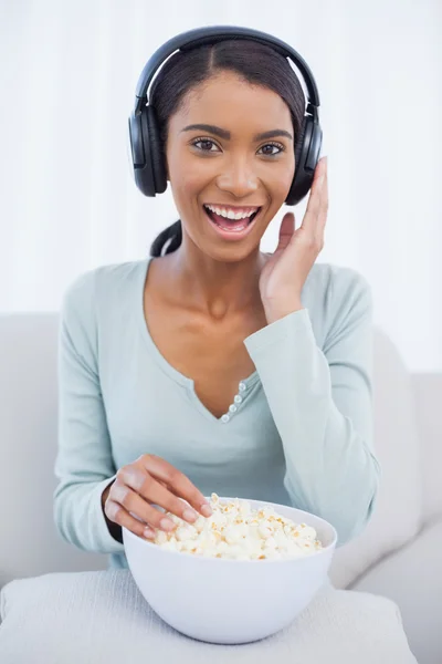Mujer atractiva comiendo palomitas de maíz mientras escucha música —  Fotos de Stock