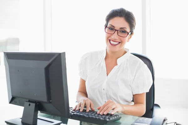 Fröhliche Geschäftsfrau, die am Schreibtisch sitzt und in die Kamera blickt — Stockfoto