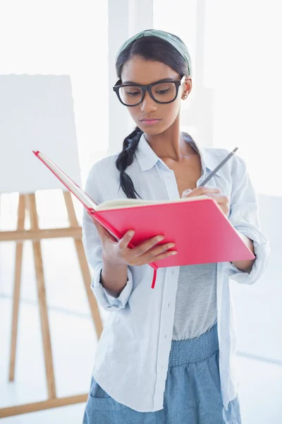 Konzentrierte attraktive Künstlerin zeichnet auf ihrem Notizbuch — Stockfoto