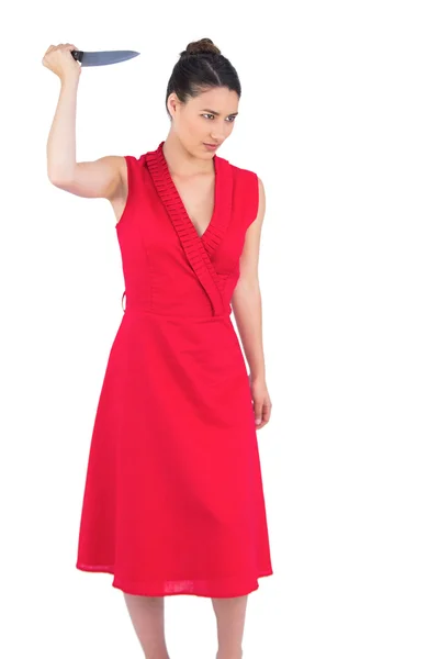 Злая элегантная брюнетка в красном платье с ножом в руках — стоковое фото