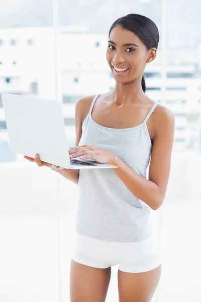 Smiling sporty model holding laptop — Stock Photo, Image