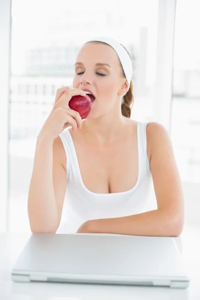 Calm pretty sportswoman eating an apple — Stock Photo, Image