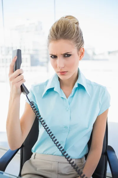 Frowning stylish businesswoman holding the phone — Stock Photo, Image