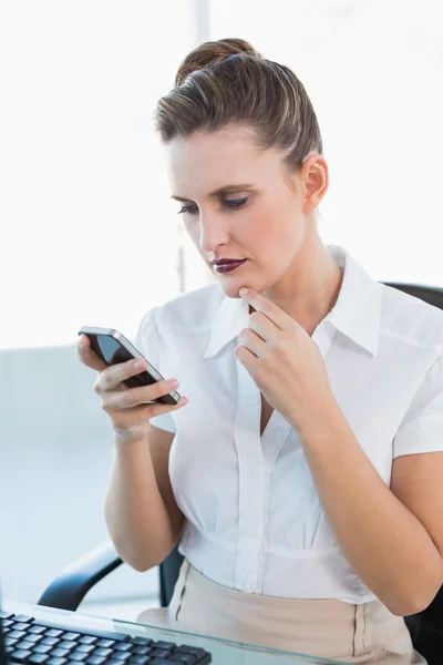 Nachdenkliche Geschäftsfrau blickt auf ihr Smartphone — Stockfoto