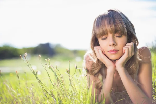 Nadenkend jonge vrouw liggen op het gras — Stockfoto